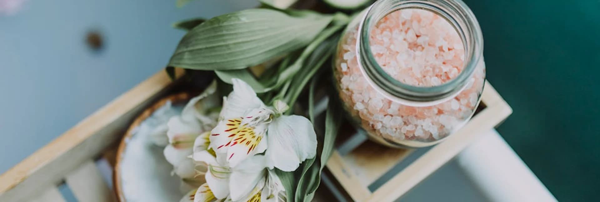 Jar of pink bath salts beside white flowers