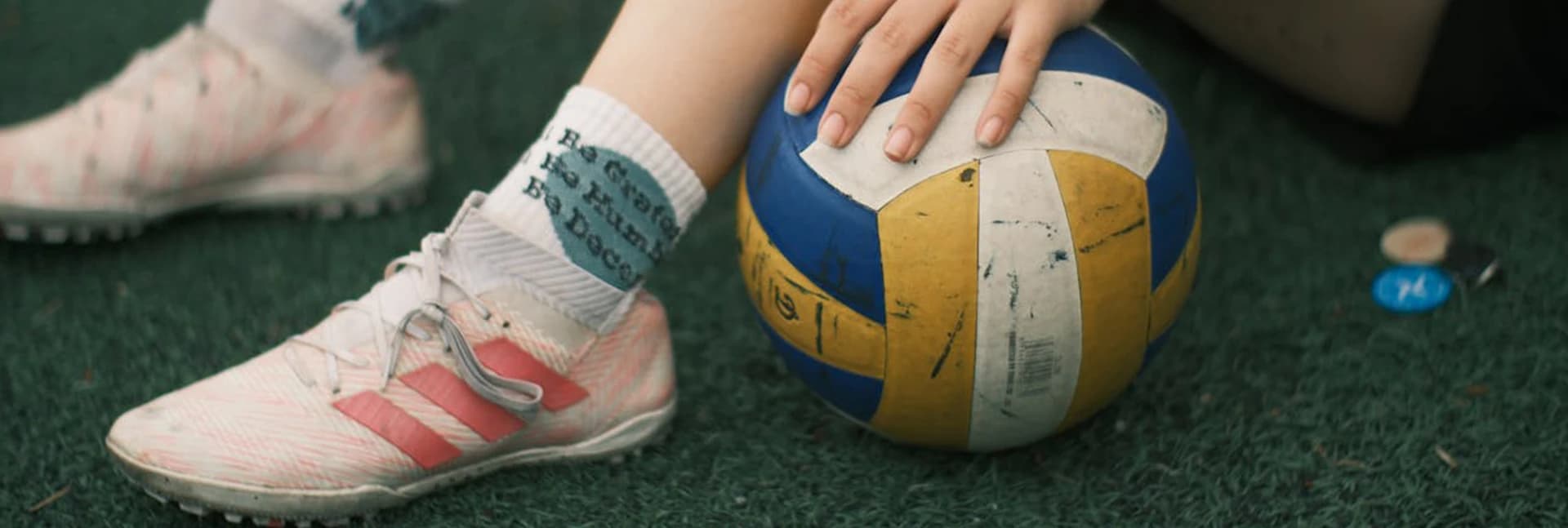 Player resting a hand on a volleyball on a court