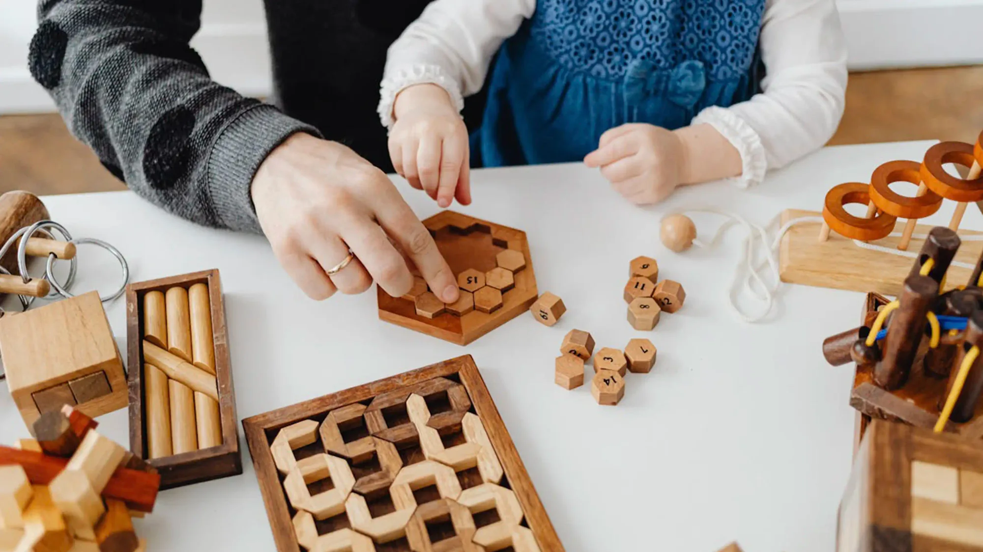 Child and adult playing with wooden puzzles at a table